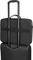 Un sac noir pour ordinateur portable est glissé sur la poignée d'une valise à roulettes.