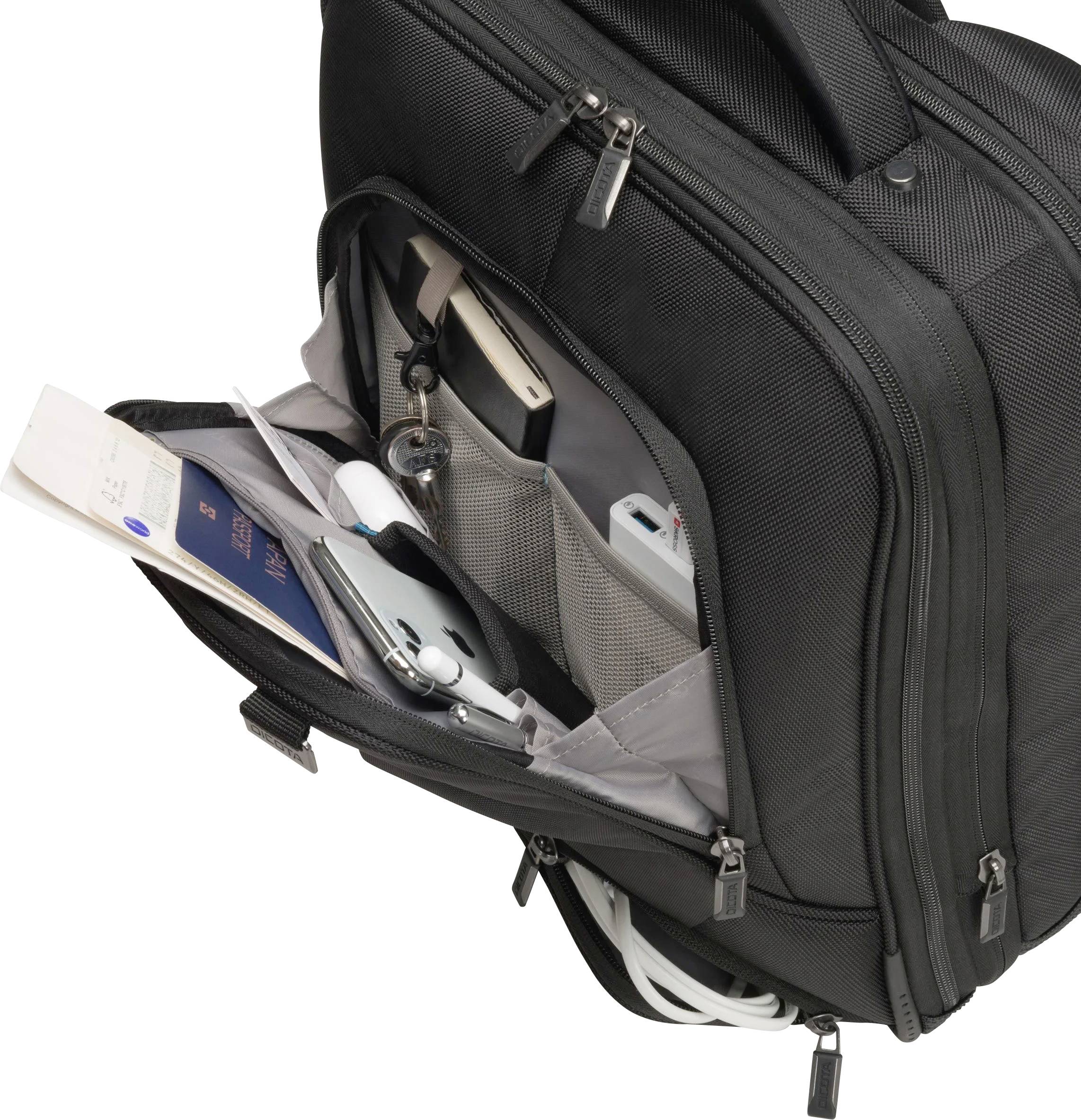 Un sac de voyage noir ouvert à plusieurs compartiments, contenant des documents de voyage, un téléphone mobile, des écouteurs et des câbles de chargement.