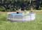 Trois personnes jouent dans une piscine ronde hors-sol dans un jardin. Une personne plonge, tandis que les autres sont assises au bord du bassin et regardent.