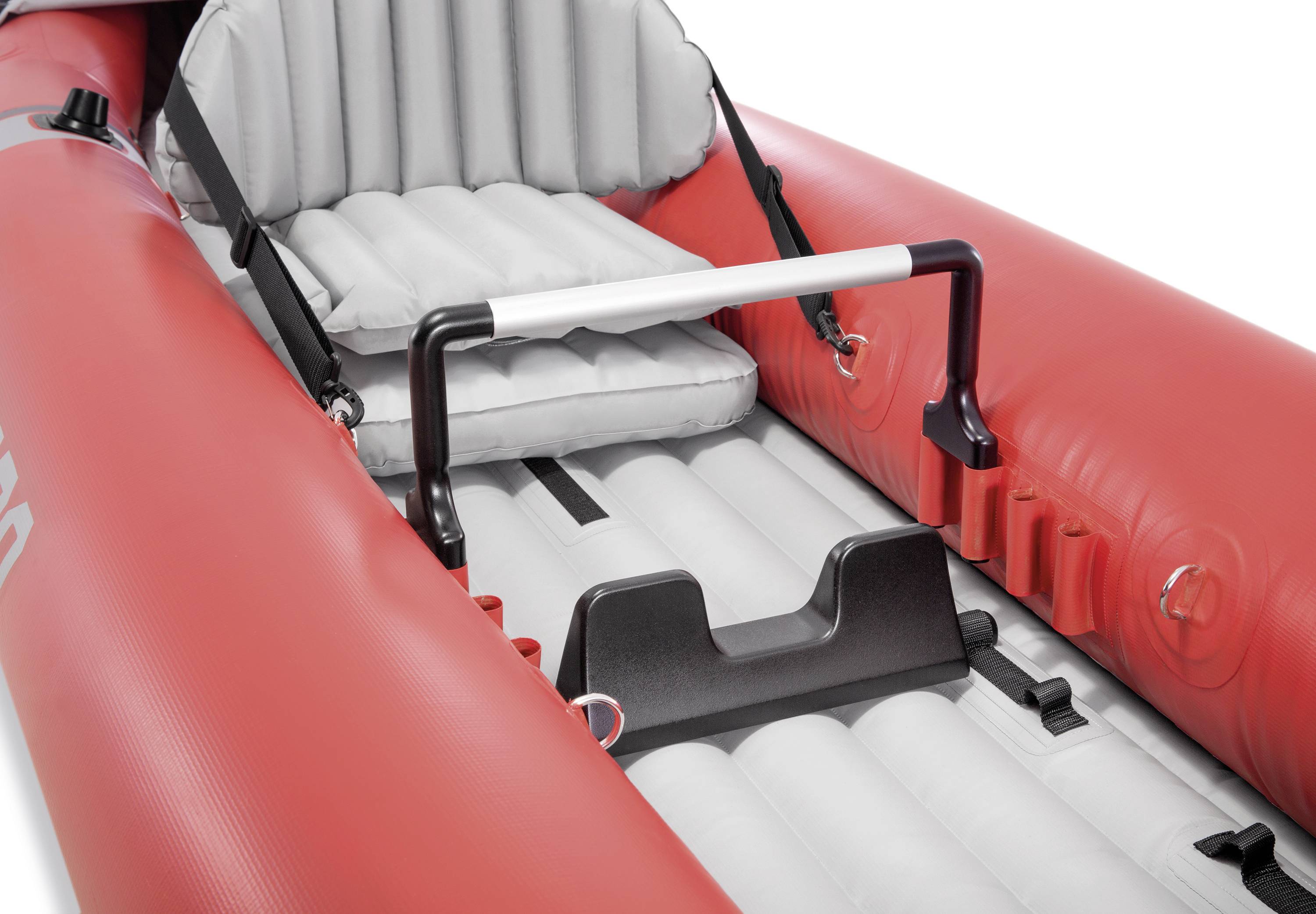 Bateau pneumatique rouge avec surface assise rembourrée grise et poignée de maintien noire. Adapté pour les descentes de rivière ou les activités de loisirs.
