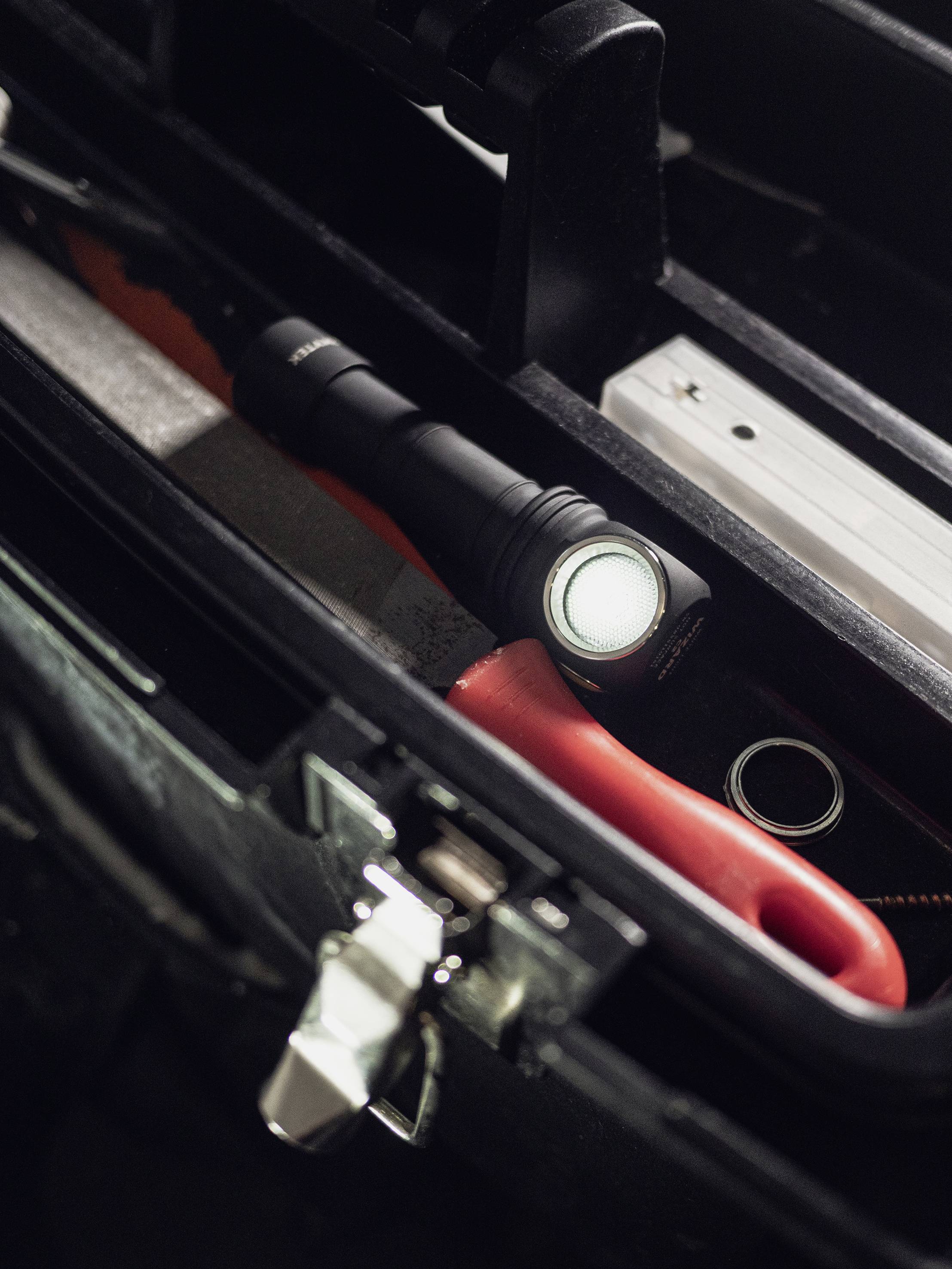 Boîte à outils comprenant une lampe de poche et des outils à poignée rouge, bien organisée ; adaptée pour les réparations et travaux manuels.