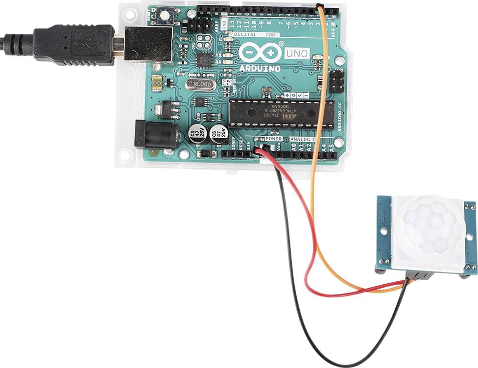 Carte Arduino Uno connectée à un capteur de mouvement via des câbles. LEDs, port USB et capteur visibles. Configuration d'un projet électronique.