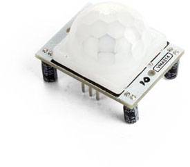 Un capteur PIR (Infrarouge Passif) sur une surface blanche montre ses six broches de connexion et ses condensateurs.