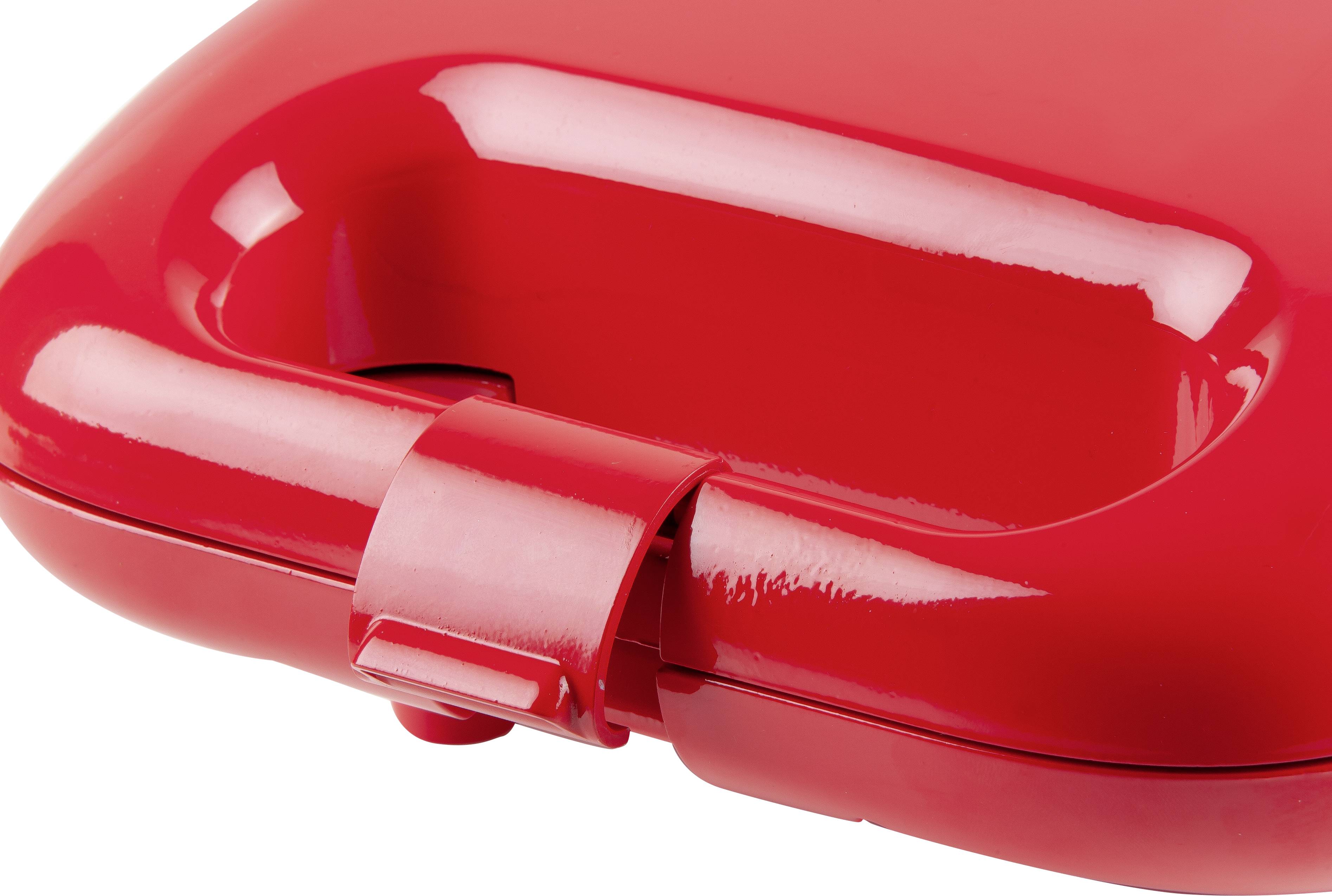 Une poignée en plastique rouge à surface brillante, probablement une partie d'une valise ou d'un appareil, présentée en gros plan.