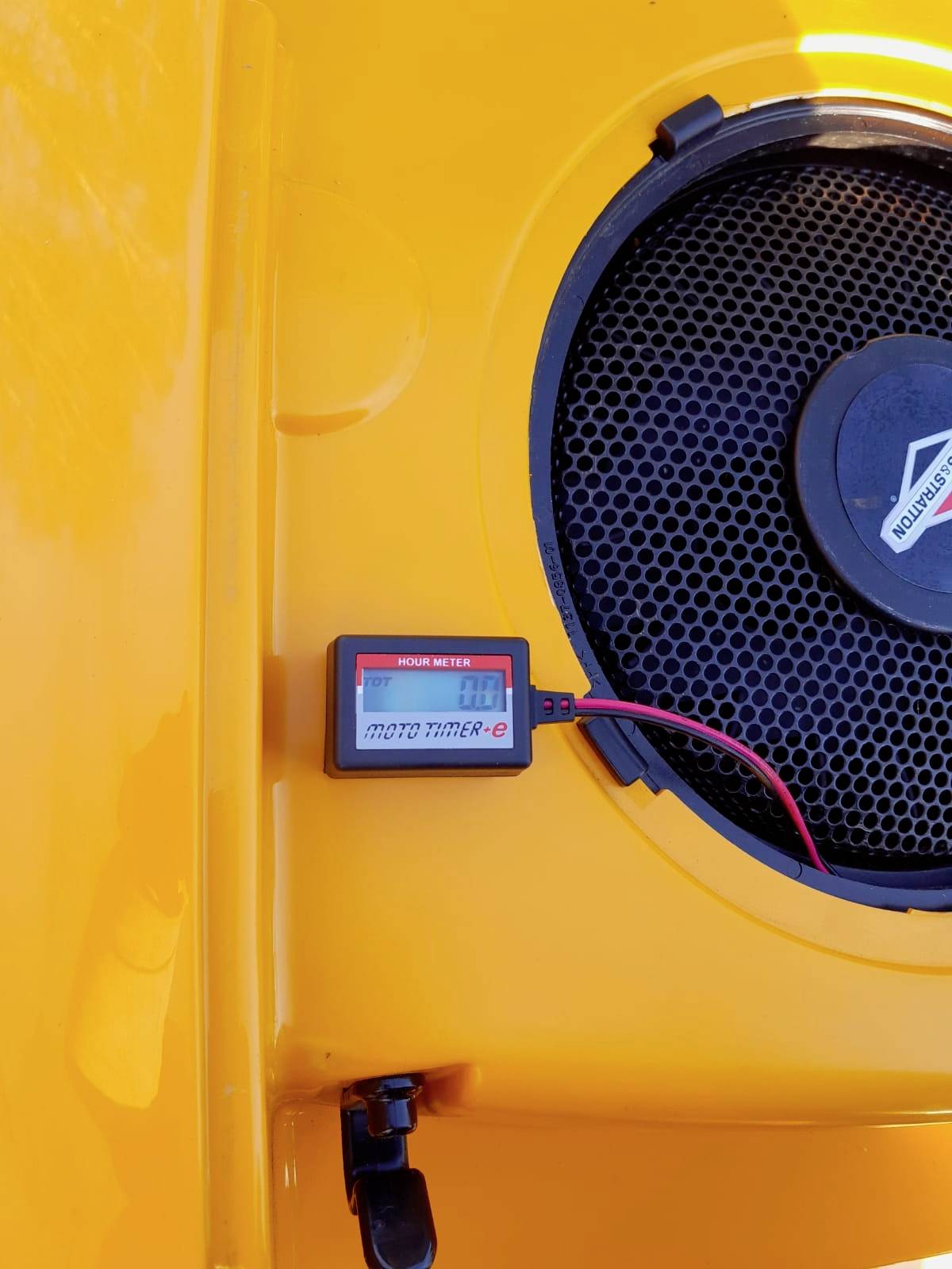 Un boîtier de machine jaune avec un compteur horaire indiquant '7,8'. Une grille de ventilation est visible.