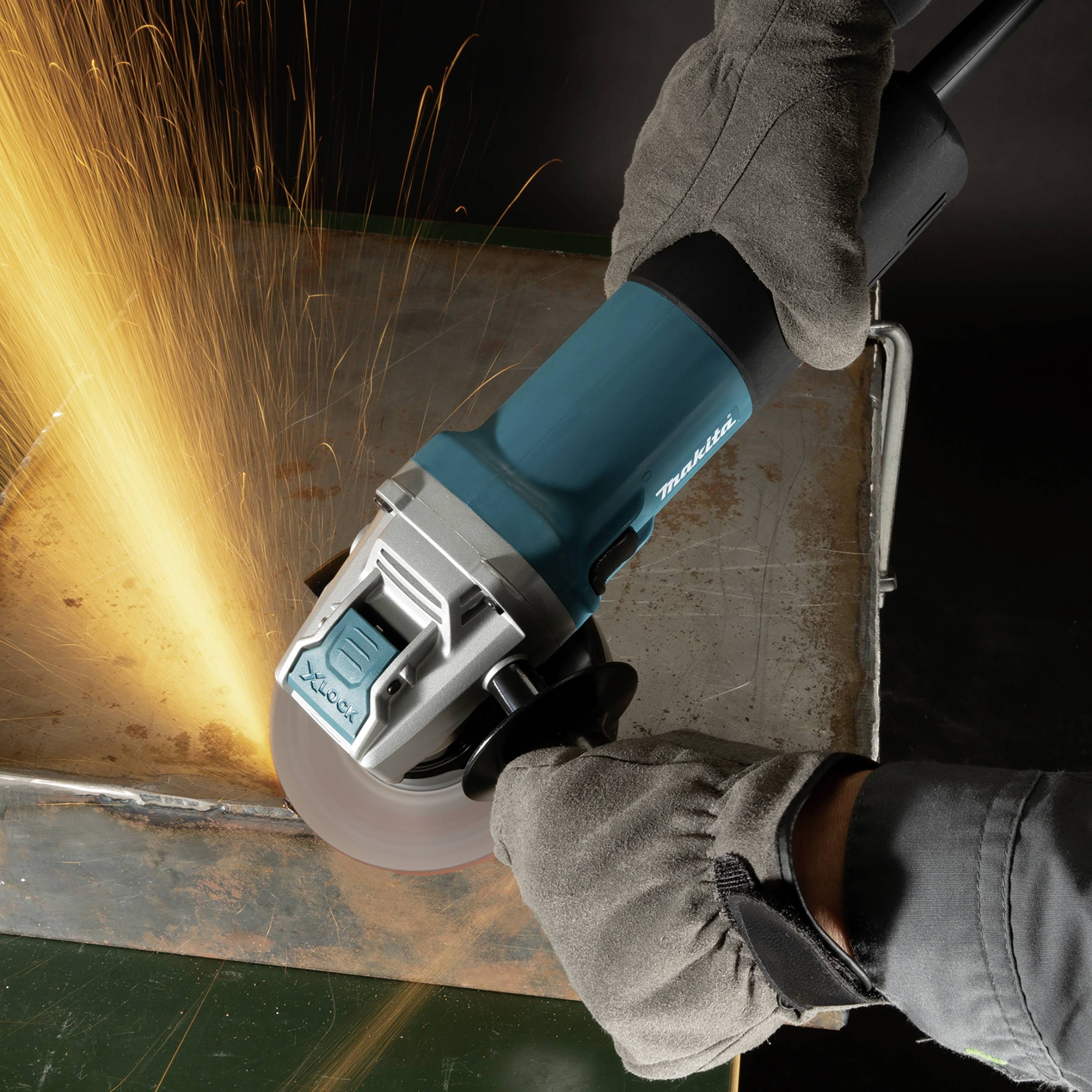 Une meuleuse d'angle génère des étincelles tandis qu'une personne portant des gants travaille le métal.