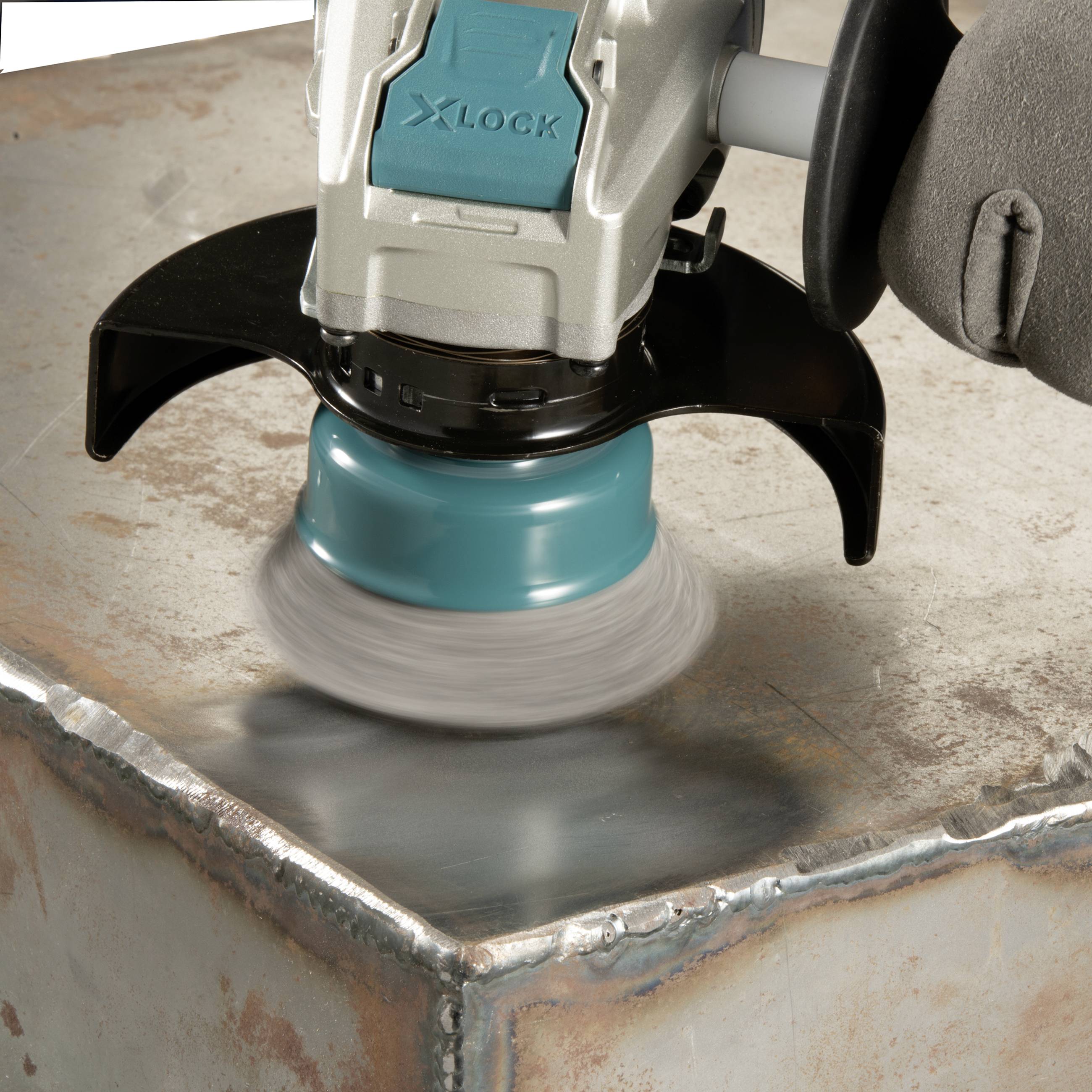 Une meuleuse d'angle avec système X-LOCK ponce une surface métallique. Une main tient la machine pour un contrôle précis.