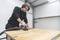 Un homme ponce la surface d'une table en bois avec une ponceuse dans un atelier.