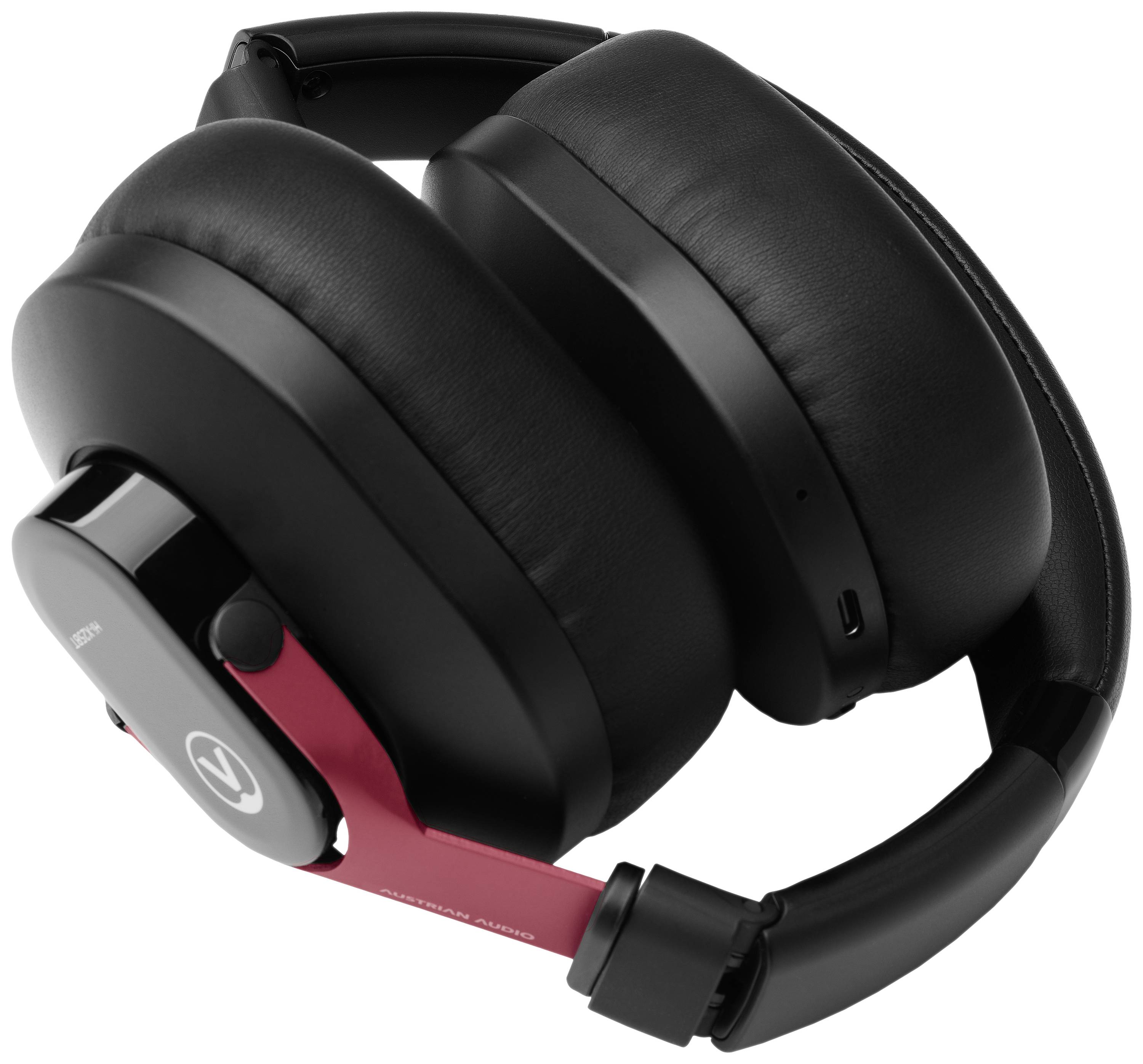 Casque audio circumaural fermé, noir et rouge, avec des coussinets d'oreille rembourrés et un design élégant, présenté de profil.