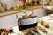 Grille-pain dans un environnement de cuisine avec deux petits pains à l'intérieur. Pain frais et confiture sur la table, fleurs en arrière-plan.
