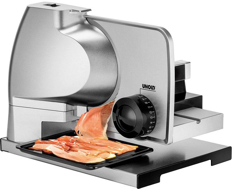 Machine à trancher électrique en acier inoxydable coupe des tranches fines de jambon sur un plateau.