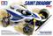 Voiture de course miniature sur emballage clair. Texte : 'Saint Dragon, 4WD, Tamiya'. Comprend une voiture miniature tout-terrain blanche et bleue avec des pneus robustes.