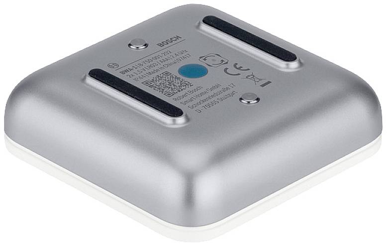 Un appareil électronique argenté, carré avec des coins arrondis. Contient des informations sur le fabricant et des symboles de certification sur sa surface supérieure.