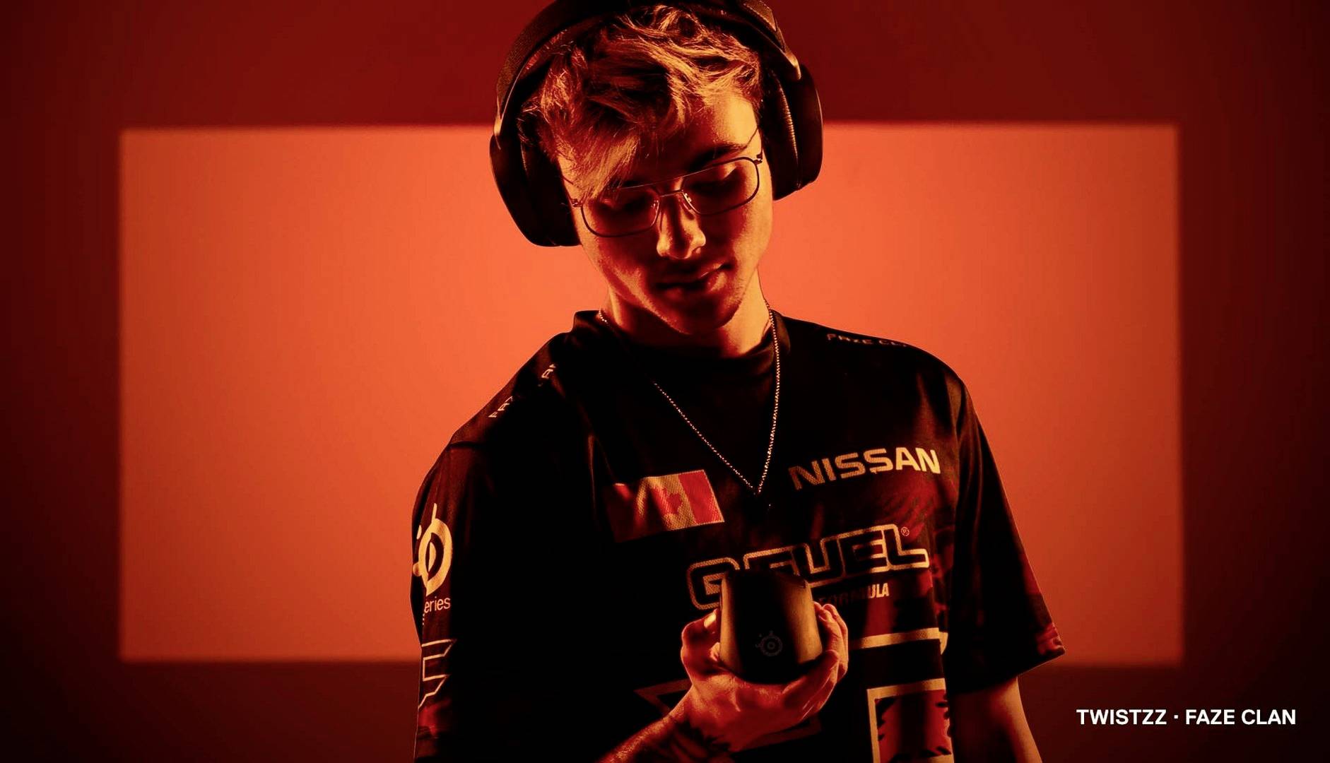 Une personne portant des lunettes et des écouteurs, vêtue d'un maillot d'esports, tient un trophée devant un fond orange.