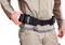 Une personne en tenue de travail porte une ceinture à outils avec plusieurs emplacements. La main ajuste la ceinture.