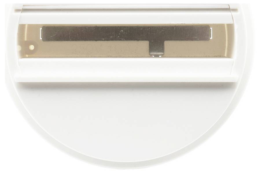 Gros plan d'un appareil en plastique blanc avec une base circulaire transparente et un petit composant rectangulaire noir à l'intérieur, présenté sur un fond uni.