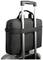 Un sac pour ordinateur portable noir est fixé sur la poignée d'une valise argentée, illustrant la fonctionnalité de voyage.