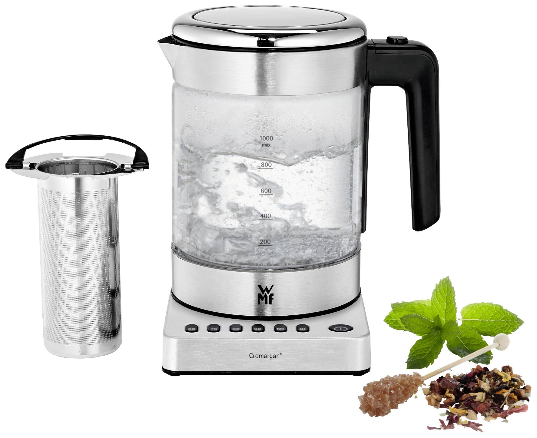 Bouilloire en acier inoxydable avec carafe en verre, eau bouillante visible à l'intérieur. À côté, un tamis à thé et des feuilles de thé en vrac à la menthe.