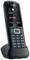 Téléphone sans fil sur sa station de charge affichant un appel entrant de 'John Smith' avec les options 'Répondre' et 'Mettre en sourdine'.