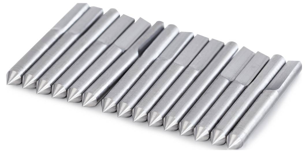 Douze chevilles métalliques argentées sont alignées sur une surface blanche. Elles sont disposées de manière uniforme.