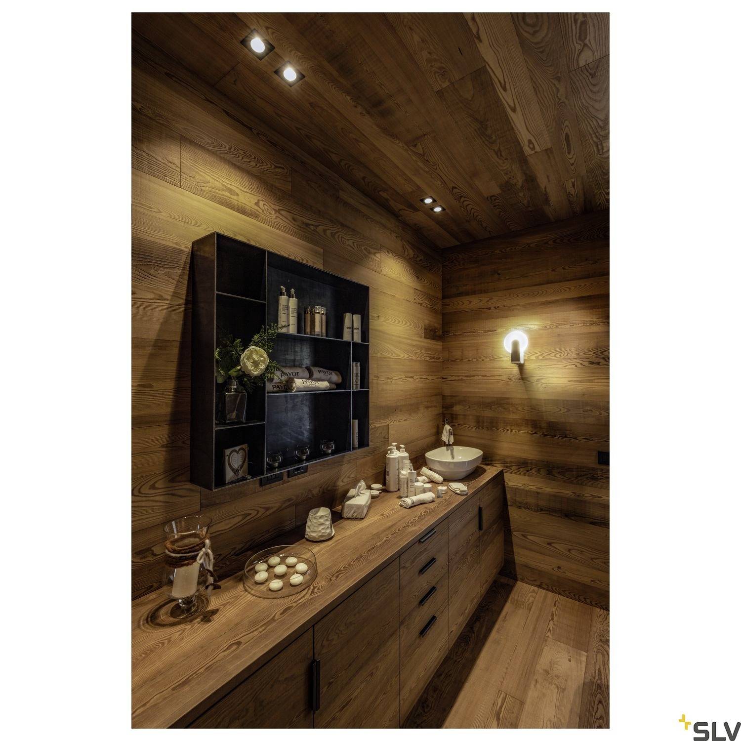 Salle de bain revêtue de bois avec un plafond fermé, des spots encastrés modernes et un lavabo minimaliste sur une tablette en bois.