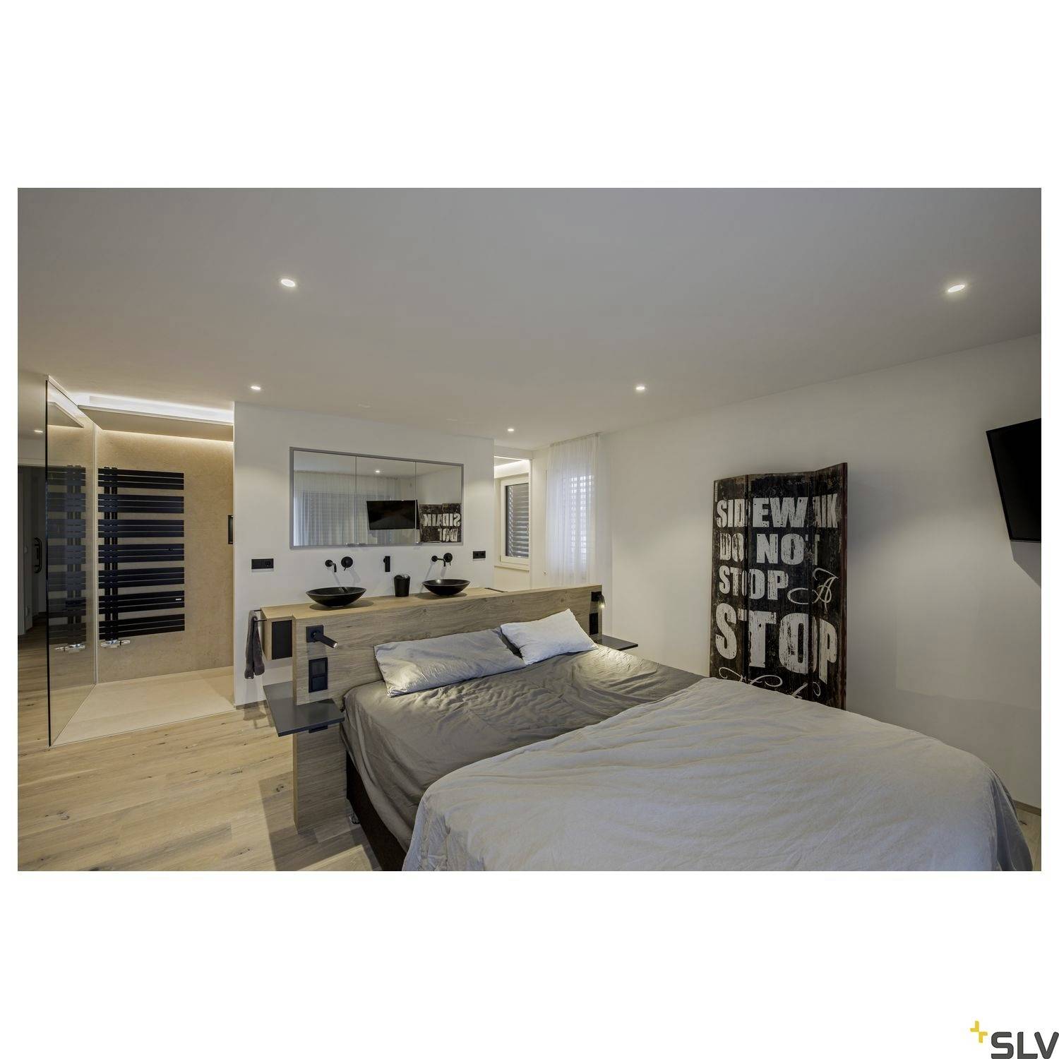 Chambre lumineuse et moderne avec un lit double, grand miroir et meubles élégants. Une toile portant l'inscription 'Sidewalk No Stop' est accrochée au mur.