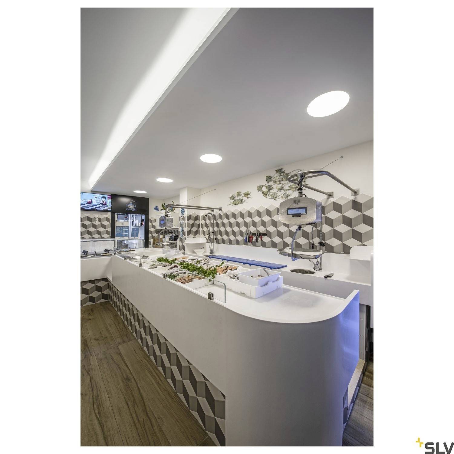 Cantine avec un bar à salade, différents plats et une décoration murale et plafonnière moderne et géométrique.