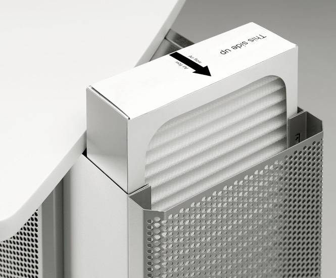 Un filtre à air est inséré dans un appareil. Le filtre est sécurisé dans une boîte portant l'inscription « Ce côté vers le haut ».