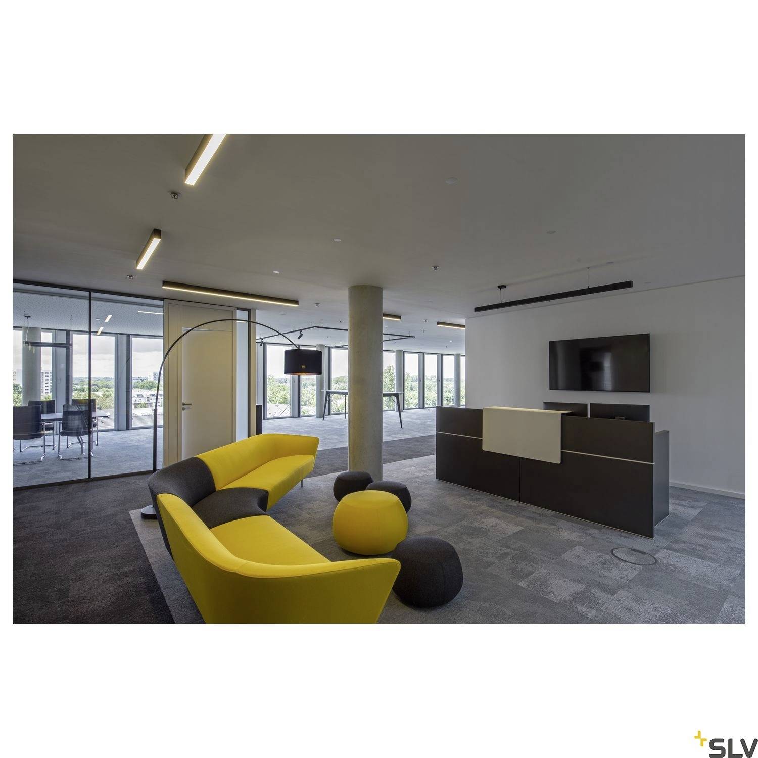 Un espace de bureau moderne avec un canapé jaune, un comptoir d'accueil noir et de grandes fenêtres. Un éclairage lumineux met en valeur le design minimaliste.