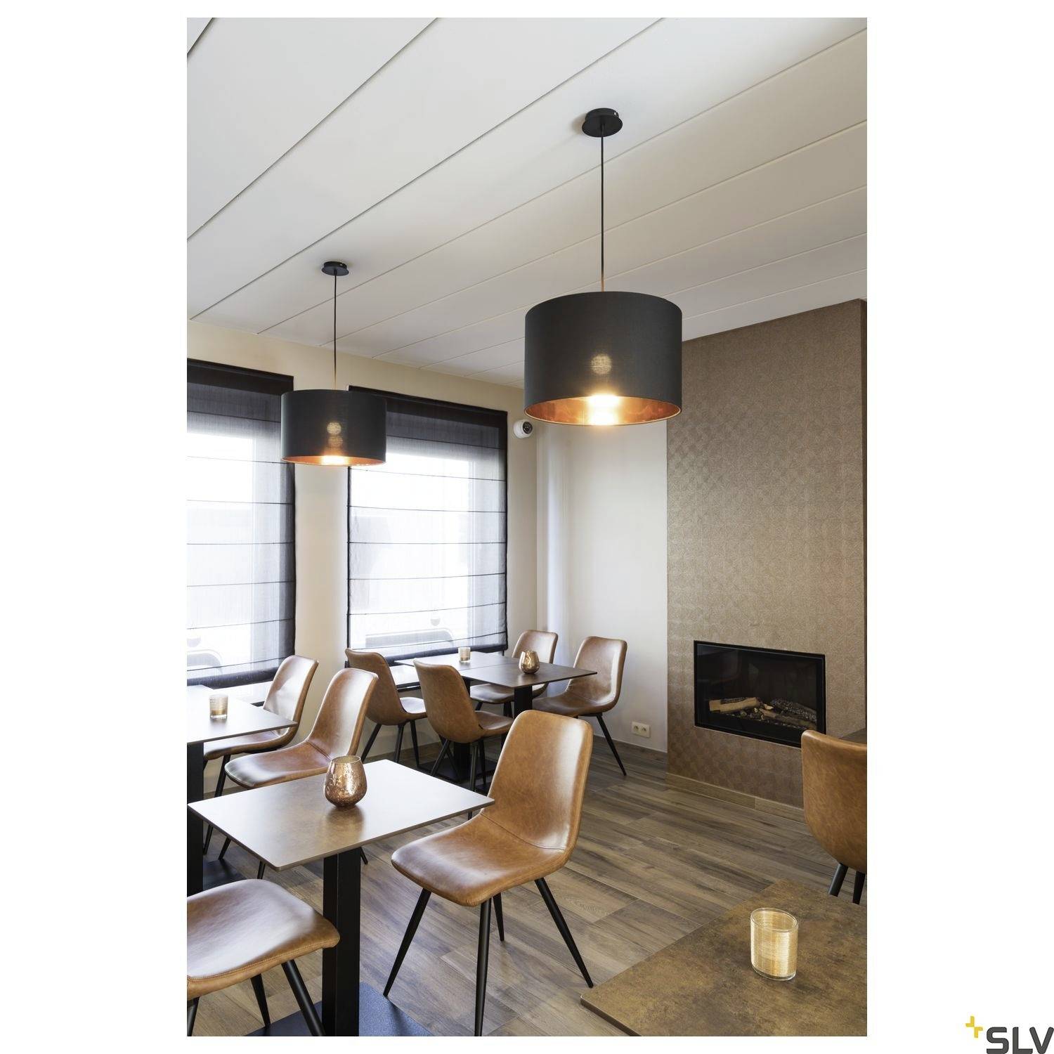 Espace repas chaleureux dans des tons de brun et de beige, avec des suspensions modernes, des fauteuils en cuir, des tables en bois et une cheminée.
