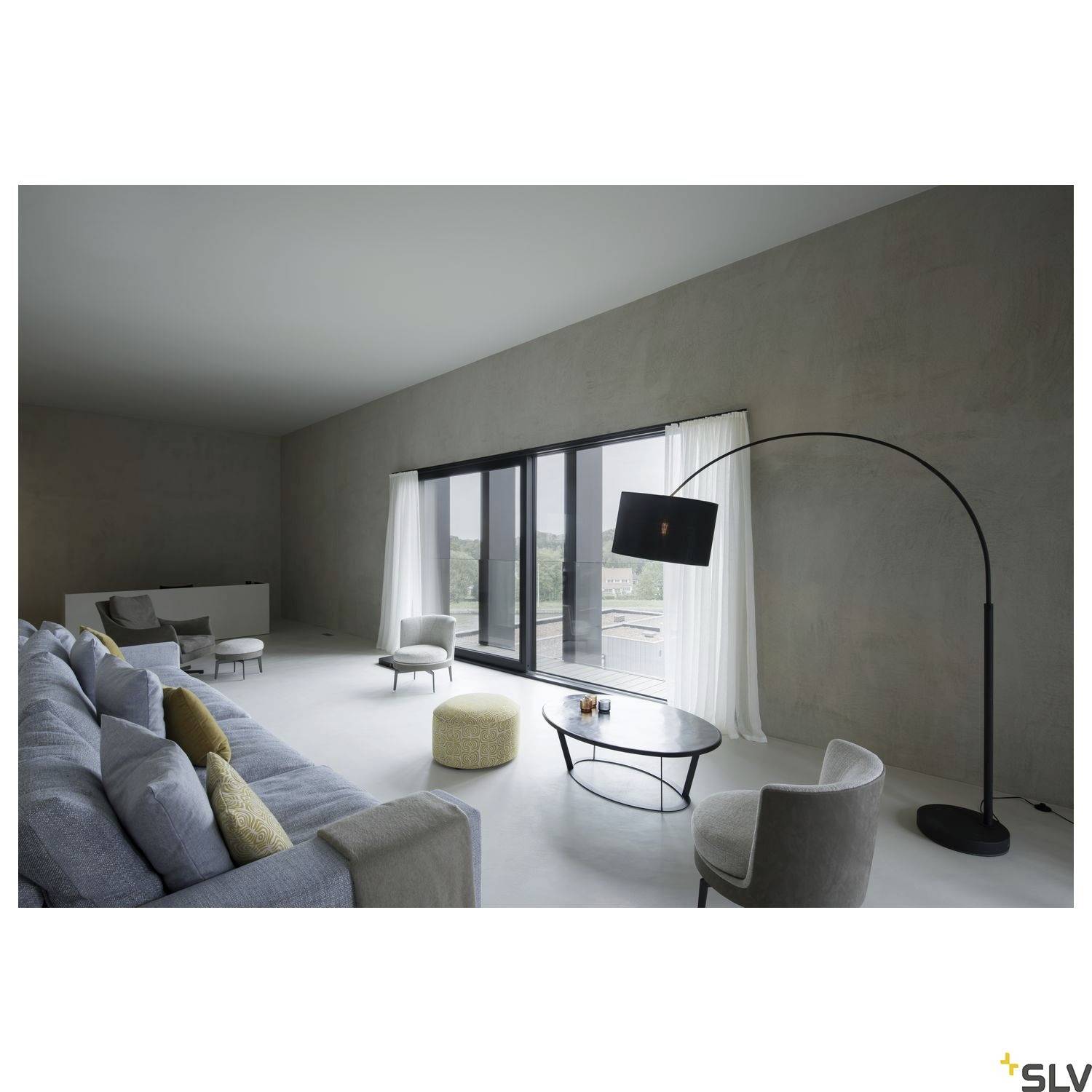Salon spacieux et moderne avec des murs gris, de grandes fenêtres, un canapé gris, un pouf doré et un lampadaire.
