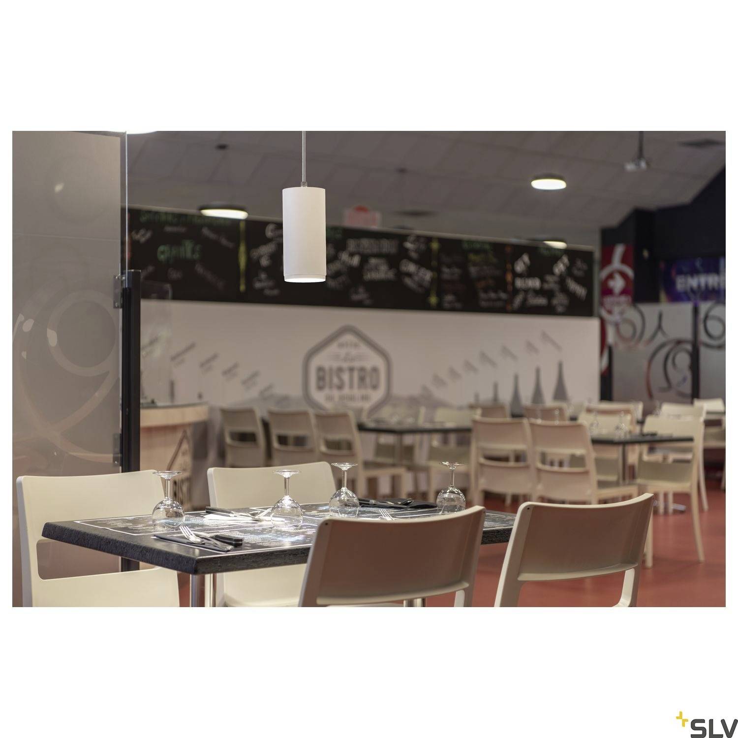 Un bistro moderne avec plusieurs tables dressées. Au fond, un tableau avec le menu est visible. Un éclairage discret crée une atmosphère chaleureuse.