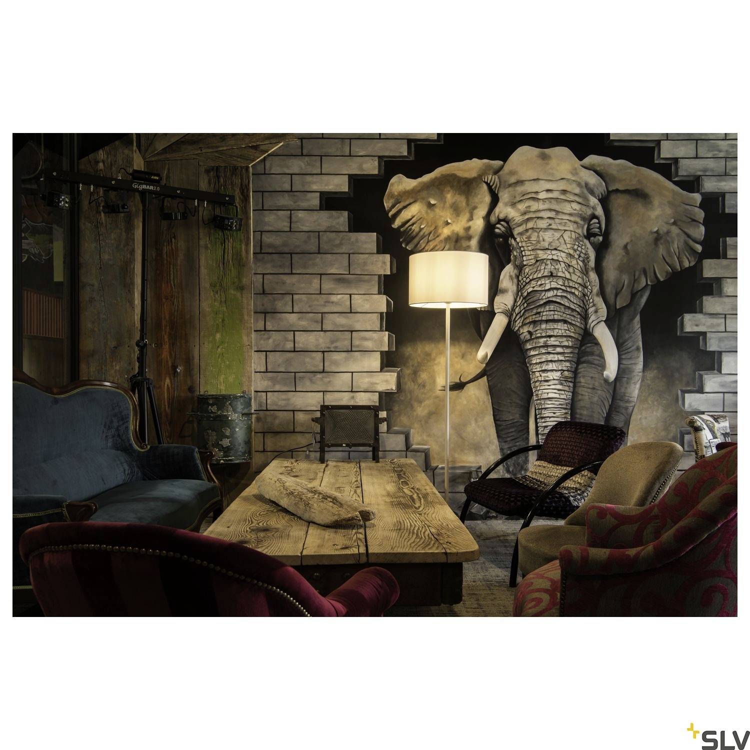 Un salon élégamment aménagé avec une grande fresque murale d'éléphant, des meubles en bois et des fauteuils confortables dans une ambiance moderne.