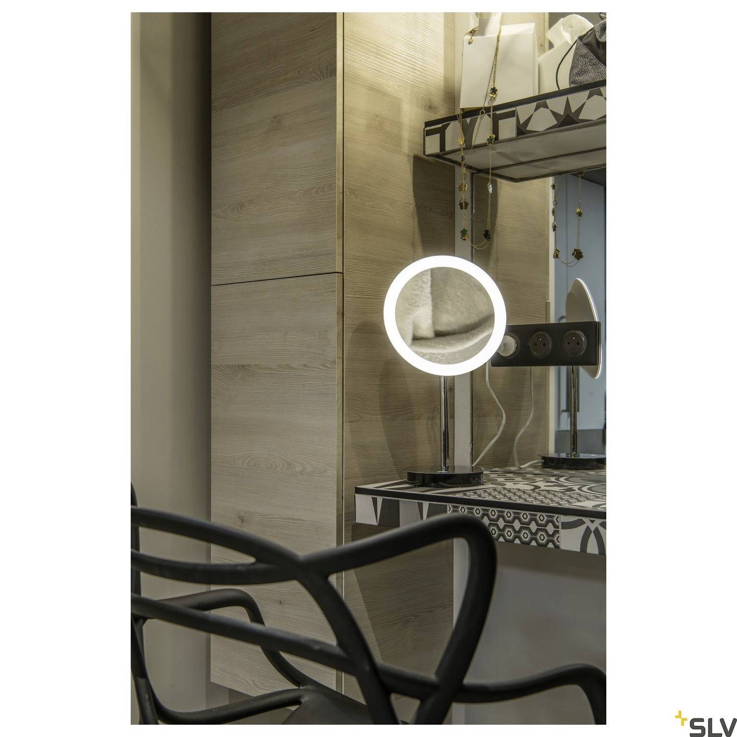 Une coiffeuse avec un miroir illuminé dans une pièce moderne, avec des armoires en bois et des éléments décoratifs en arrière-plan.