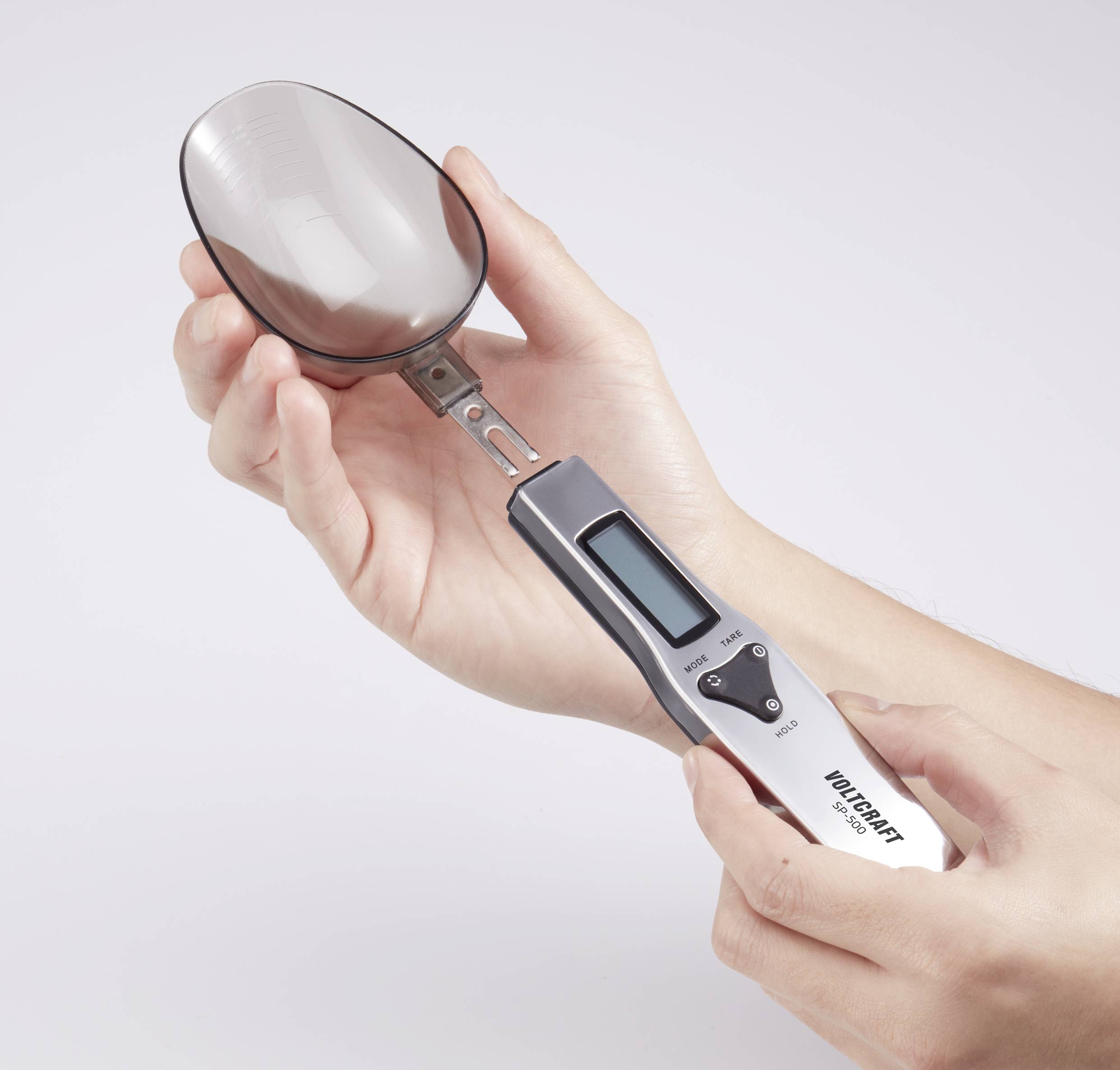 Balance électronique de précision avec un écran, tenue dans les deux mains. Elle affiche la mesure du poids de petites quantités.