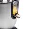 Une presse-agrumes électrique argentée avec un récipient transparent et un bec verseur, montrant du jus d'orange frais coulant.