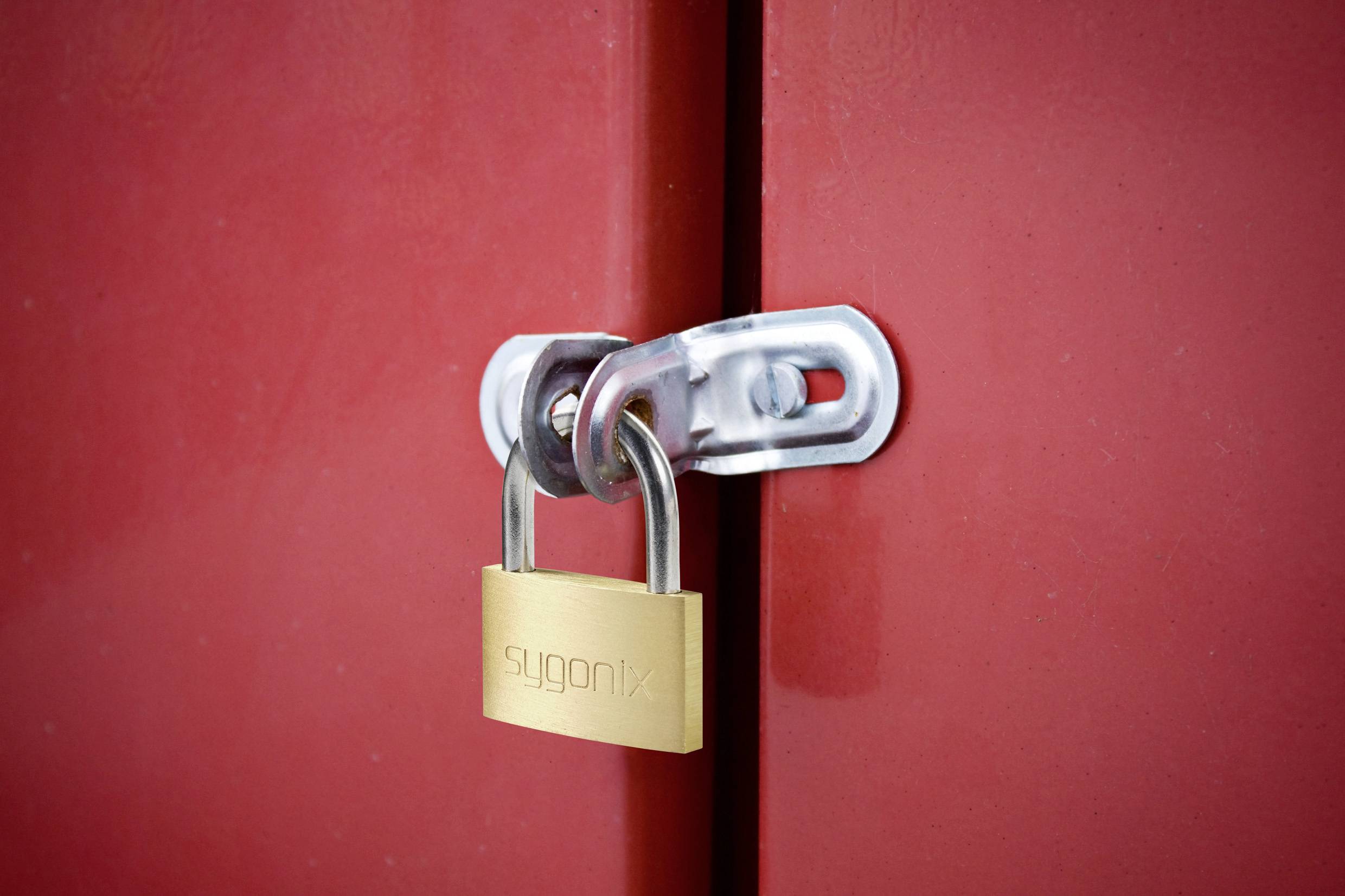 Un cadenas doré verrouille les portes d'un placard rouge.