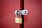 Un cadenas doré verrouille les portes d'un placard rouge.