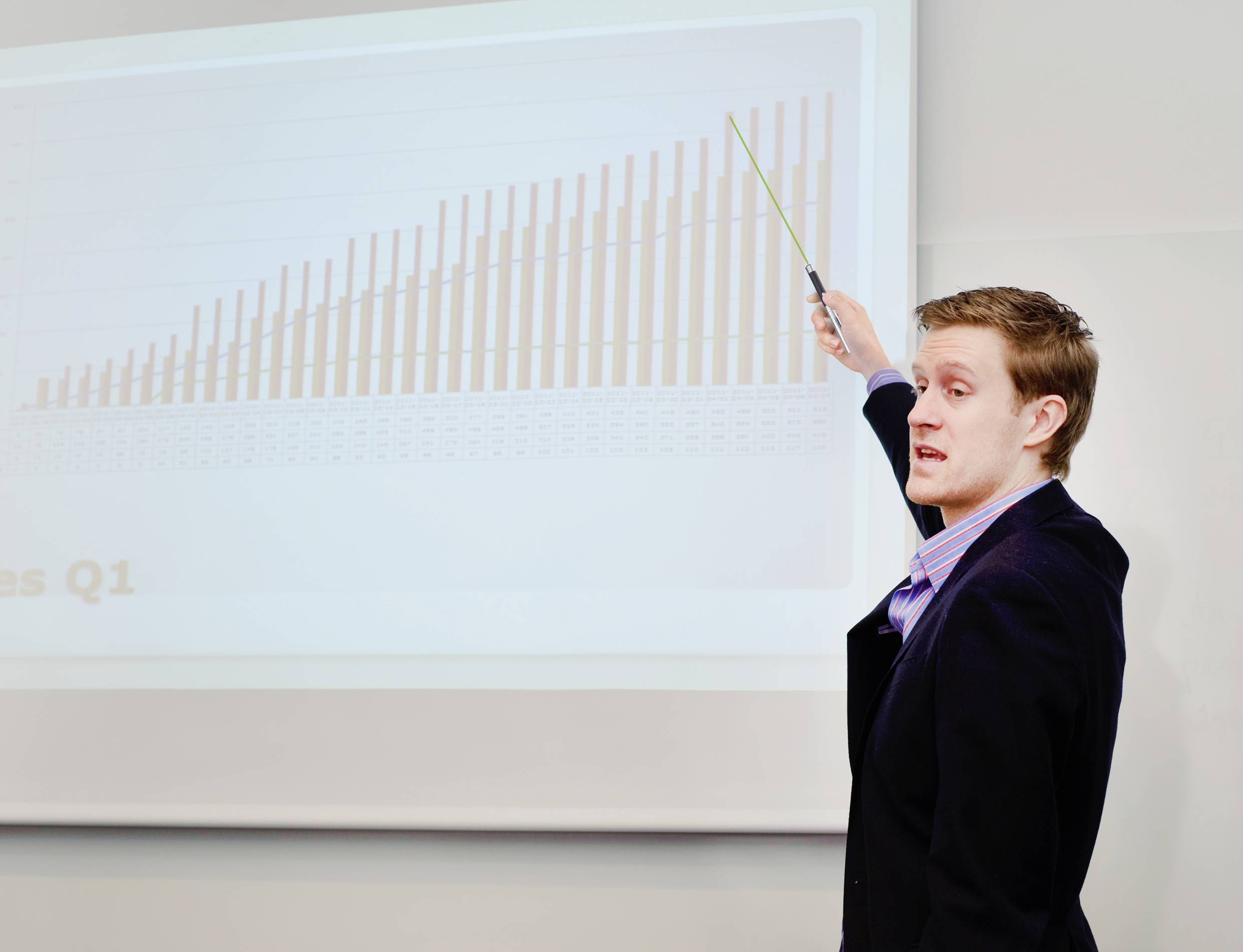 Un homme présente un graphique à barres montrant l'augmentation des chiffres de vente pour le premier trimestre et pointe du doigt les données.
