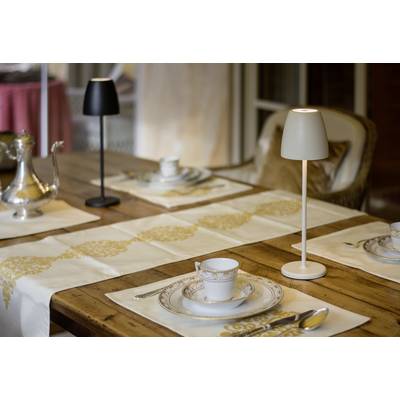 Une table élégamment dressée avec un service à thé et des lampes de table sur une table en bois. La table est préparée pour quatre personnes.