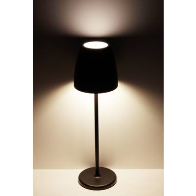 Une lampe de table avec un abat-jour noir est posée sur une surface blanche. Elle diffuse une lumière douce vers le haut et vers le bas.