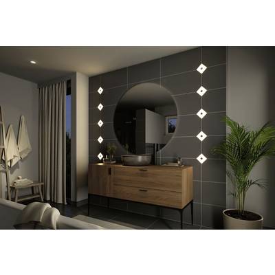 Une salle de bain élégante avec un miroir rond, une commode en bois et des appliques murales modernes. Une plante est placée à droite.