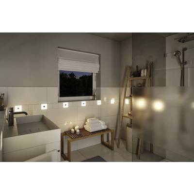 Salle de bain moderne la nuit, illuminée d'une lumière chaleureuse. Lavabo à gauche, banc en bois avec des serviettes et des bougies à droite.