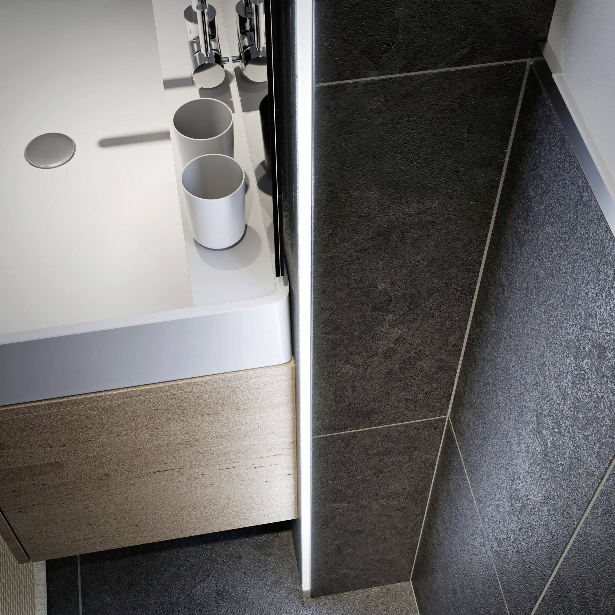 Un lavabo en céramique blanche avec deux gobelets blancs dessus. Il se trouve dans une salle de bain moderne aux carrelages sombres.