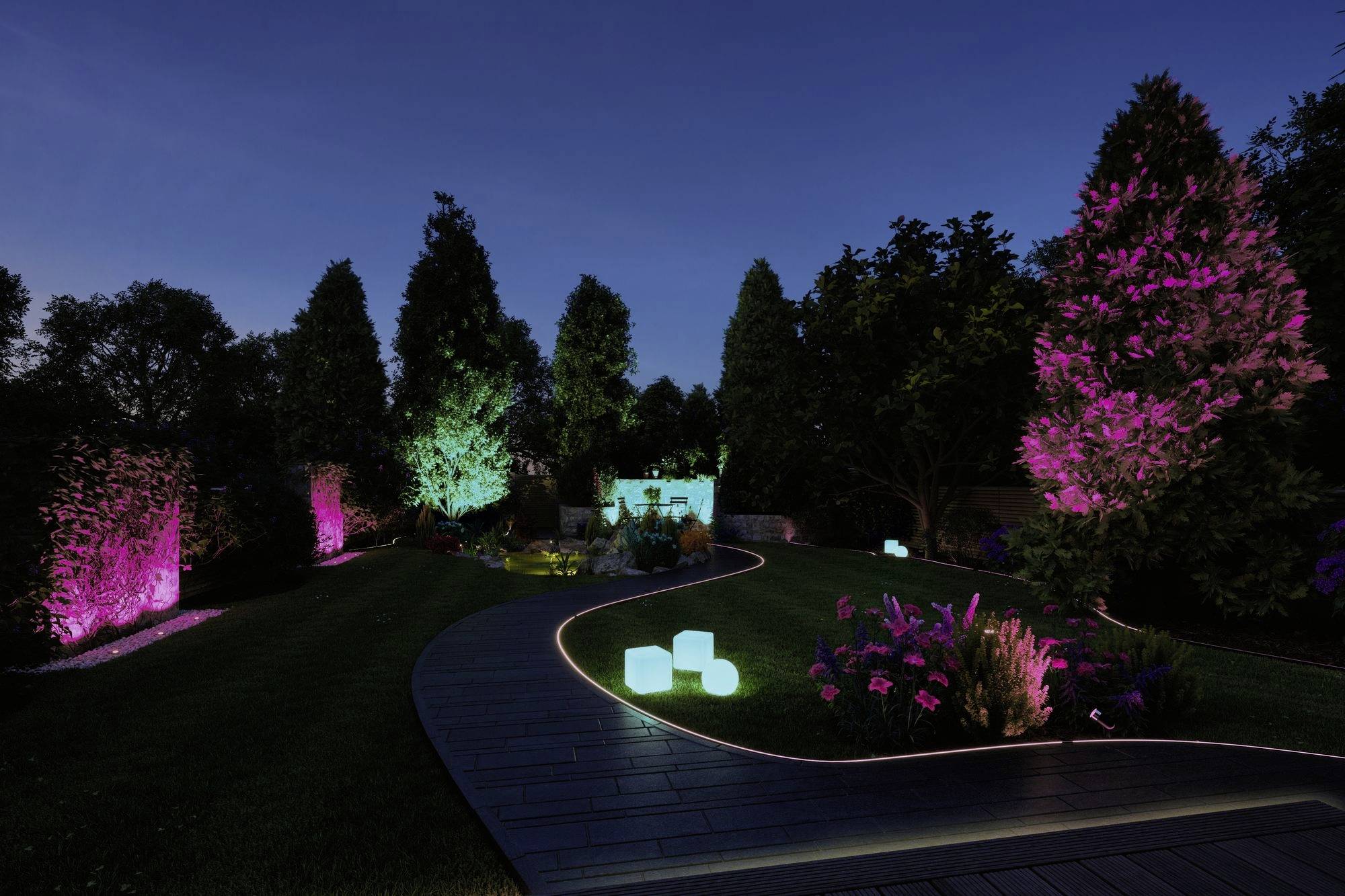 Un jardin nocturne avec des arbres et des arbustes illuminés de couleurs ; des cubes lumineux marquent un chemin sinueux.