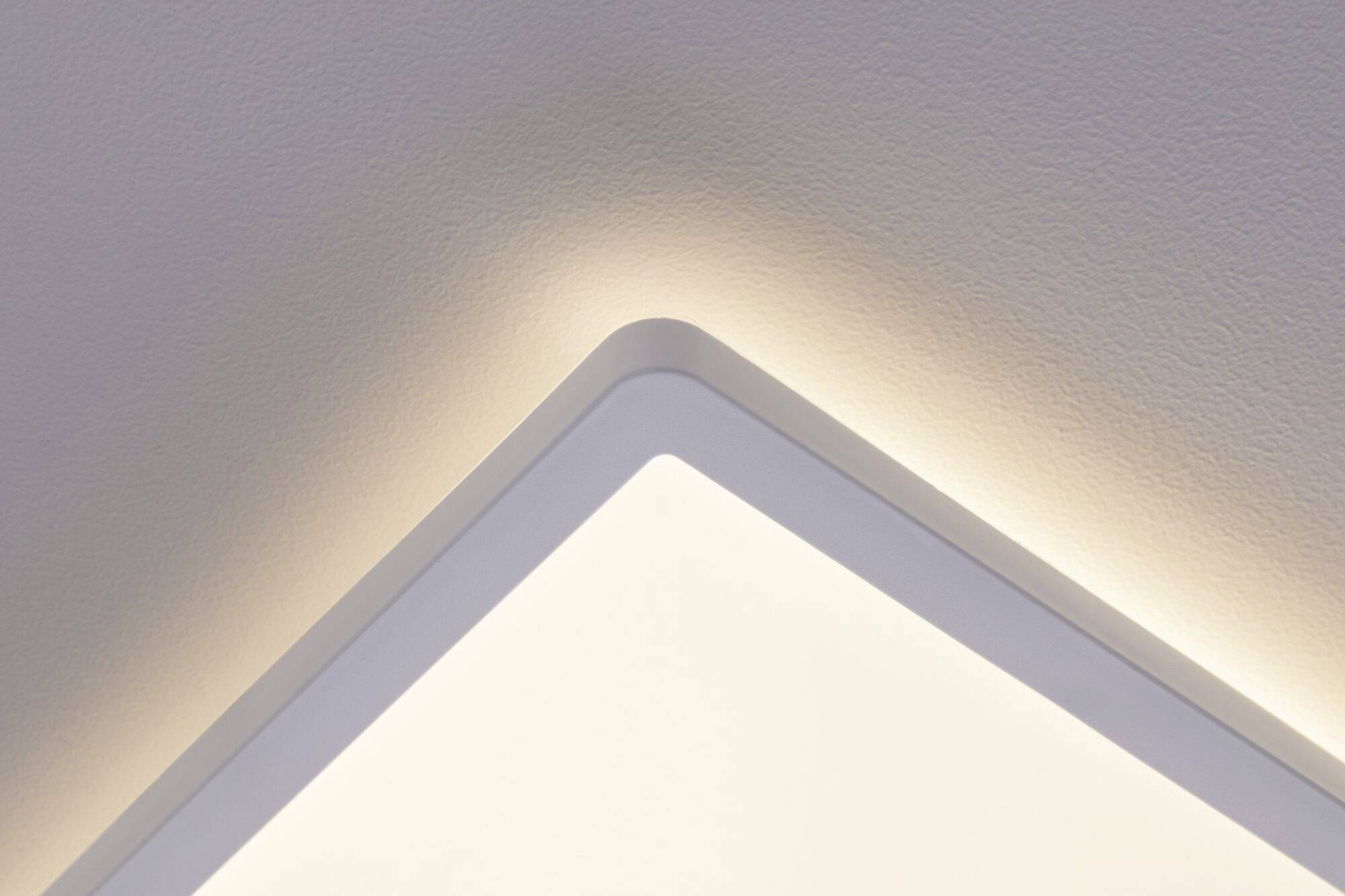 Un coin d'un luminaire de plafond à LED avec un éclairage doux et indirect, illuminant la zone murale et créant une ambiance moderne.