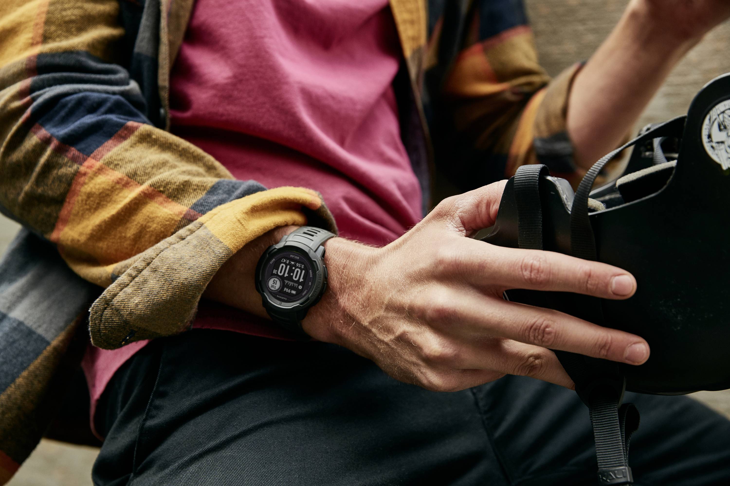 Une personne tient un casque de vélo et porte une montre digitale au poignet. La montre affiche 10:01.