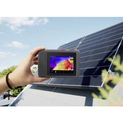 Une main tient une caméra thermique au-dessus d'un panneau solaire ; l'écran affiche une image thermique du panneau pour vérifier la répartition de la température.
