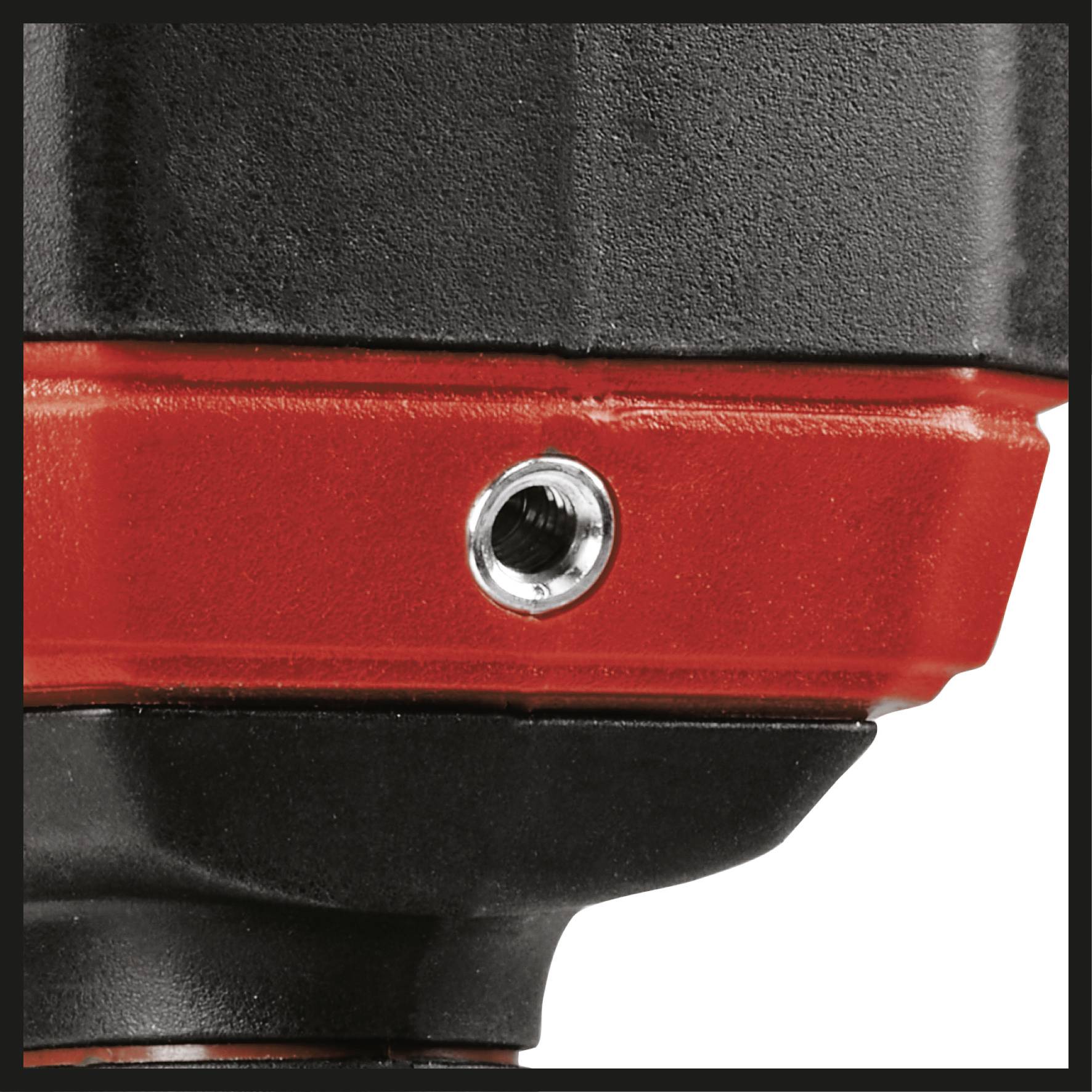 Gros plan d'un dispositif noir et rouge avec une ouverture métallique, probablement un raccord ou une fixation sur un outil.