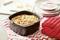 Un gâteau carré dans un moule noir, recouvert de lamelles d'amandes. Il est posé sur un tissu à motifs rouge et blanc, à côté de gants de four.